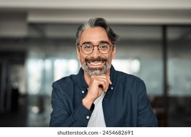 Happy middle aged 50 year old professional business man, smiling older executive ceo manager, smiling entrepreneur wearing glasses sitting at desk in office working looking at camera, portrait.