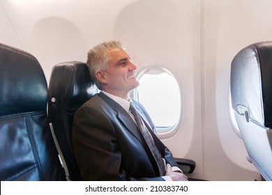 Happy Middle Aged Airplane Passenger Relaxing During Flight On Air Plane 