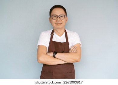 Happy middle aged Asian man waiter Entrepreneur looking at camera. Chinese millennial businessman wear apron arms crossed isolated green pastel color background. Start up small business owner concept. - Powered by Shutterstock