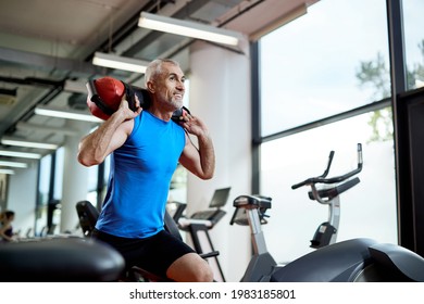 Happy Middle Aged Athlete Carrying Sandbag On His Shoulders While Working Out In A Gym. 