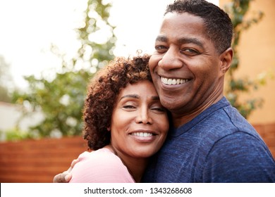 Happy middle aged black couple embracing smile to camera, close up