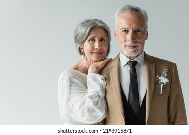 happy middle aged bride in white wedding dress leaning on shoulder of bearded groom isolated on grey - Powered by Shutterstock