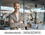 Happy middle aged business man entrepreneur looking at camera outdoors. Smiling confident mature businessman professional executive, successful lawyer wearing suit standing arms crossed, portrait.