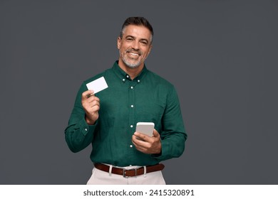 Happy middle aged business man, smiling mature businessman holding mobile phone and credit debit card mockup using banking finance app making online purchase on smartphone isolated on gray background.