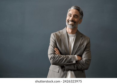 Happy middle aged business man looking away at copy space. Smiling confident 50 years old mature professional businessman executive ceo manager or entrepreneur standing at gray office wall background.