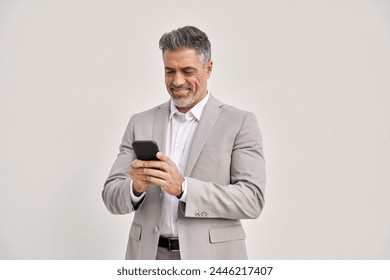 Happy middle aged business man wearing suit using mobile cell phone looking at smartphone standing isolated on white. Smiling old businessman holding mobile cellphone making banking financial payment. - Powered by Shutterstock