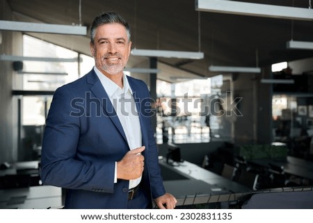 Happy middle aged business man ceo standing in office. Smiling mature confident professional executive manager, confident businessman leader wearing blue suit posing for corporate portrait.