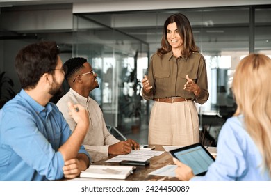Happy middle aged business woman executive ceo leader discussing project management planning strategy working with diverse colleagues company team at office corporate board group meeting.