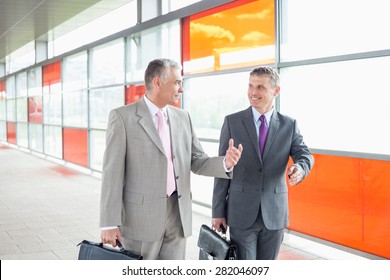 Happy Middle Aged Businessmen Talking While Walking In Railroad Station