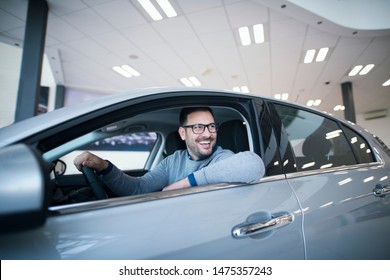 Happy Middle Aged Caucasian Car Buyer Sitting In Brand New Vehicle Looking Aside And Smiling In Local Dealership Showroom. Car Purchase.