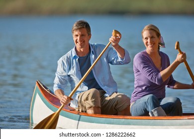 Happy Middle Aged Couple Canoeing On A Lake.