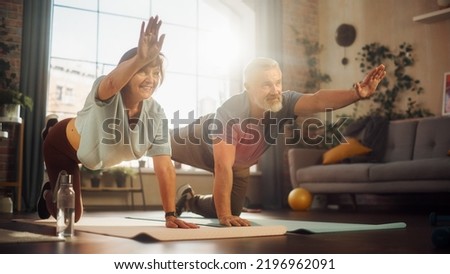 Happy Middle Aged Couple Doing Gymnastics and Yoga Stretching Exercises Together at Home on Sunny Morning. Senior Man and Woman Motivate Each Other to be Healty. Lifestyle and Fitness.