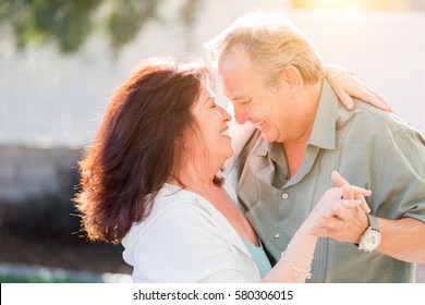 Happy Middle Aged Couple Enjoy A Romantic Slow Dance Outside.