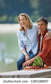 Happy Middle Aged Couple Enjoying A Healthy Fruit Picnic In The Park.