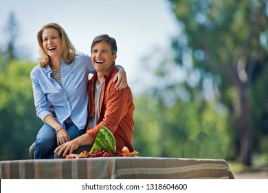 Happy Middle Aged Couple Enjoying A Picnic In A Park.