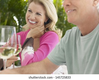 Happy Middle Aged Couple Holding Wine Glasses At Outdoor Table