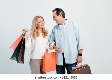 Happy Middle Aged Couple Holding Shopping Bags And Smiling Each Other Isolated On White