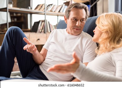 Happy middle aged couple talking and lying on bed at home   - Powered by Shutterstock