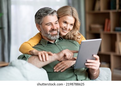 Happy Middle Aged Couple Using Digital Tablet While Relaxing In Living Room Together, Smiling Mature Man And Woman Shopping Online, Browsing Internet Or Checking New Application, Closeup Shot - Powered by Shutterstock