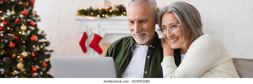 happy middle aged couple watching movie on laptop near decorated christmas tree, banner - Powered by Shutterstock