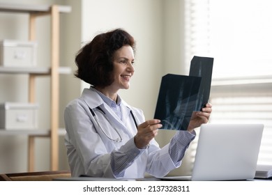 Happy Middle Aged Doctor Woman Satisfied With Patients Bones, Joints Roentgen Screening Result, Reviewing Xray Radiography Images, Smiling. Medical Professional, Trauma Expert Examining Scans