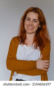 Happy Middle Aged Ginger Haired Woman In Her 40s Over White Wall. Employee In Casual Outfit Looking At The Camera. Female With Long Hair, Cheerful Freelancer Business Portrait. Copy Space