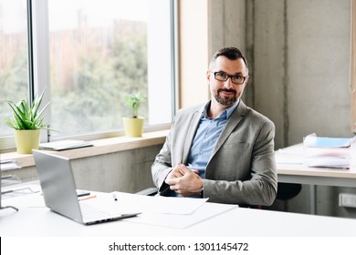 Happy middle aged handsome businessman in shirt working on laptop computer in office. Man working in office - Shutterstock ID 1301145472