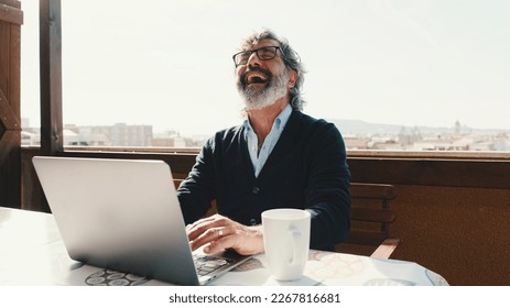 Happy middle aged man communicates remotely using laptop. Working from home office - Powered by Shutterstock