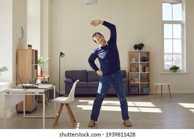 Happy middle aged man doing fitness exercise during working day at office workplace. Energetic remote or freelance worker enjoying warm up stretching at home. Wellness and caring about health concept - Powered by Shutterstock