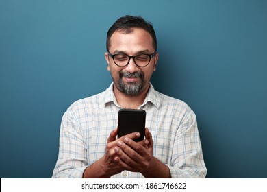 Happy Middle Aged Man Of Indian Origin Checking His Mobile Phone
