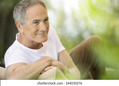 Happy Middle Aged Man Reclining On Deck Chair In Garden