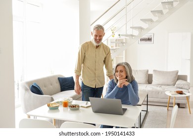 Happy Middle Aged Mature 50s Family Couple Having Fun Using Laptop Computer At Home. Smiling Senior Older Mature Husband And Wife Laughing Watching Tv Online Or Having Virtual Meeting In Living Room.