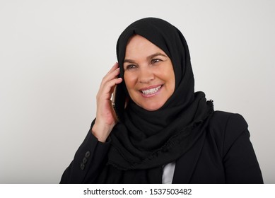 Happy middle aged Muslim Woman wearing hijab speaking on the phone, having a nice conversation with someone. - Powered by Shutterstock