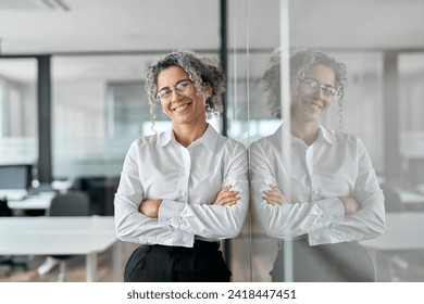 Happy middle aged professional business woman standing in office, portrait. Smiling mature senior female corporate leader, confident lady executive manager arms crossed looking at camera. - Powered by Shutterstock