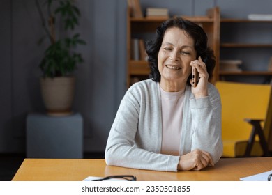 Happy middle aged senior woman talking on smartphone with family friends. Older mature lady with cell phone chatting with grown up children, resting in at home. Older generation modern tech usage - Powered by Shutterstock