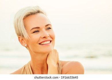 happy middle aged woman elegant looking and feeling confident on beach. spf useing concept. short haircut hairstyle