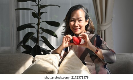 Happy Middle Aged Woman Holding Heart Shape. Elderly Care, Insurance, Heart Health And Quality Of Life For Elderly Concept