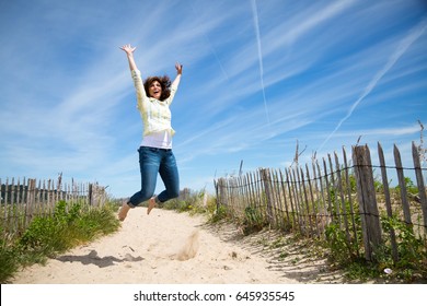 Happy Middle Aged Woman Jumping On The Beach Crazy For Vacation