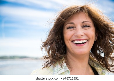 Happy Middle Aged Woman With Messy Hair Laughing On The Beach