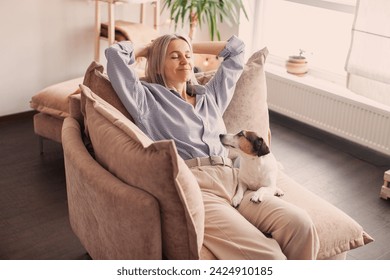 Happy middle aged Woman Relaxing at home reclining on Sofa with her hands behind her head looking upwards with a dreamy smile of pleasure - Powered by Shutterstock