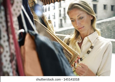 Happy Middle Aged Woman Shopping For Bags On Market Stall