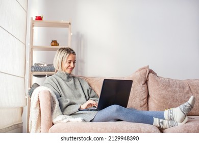 Happy middle aged woman using her laptop on the sofa at cozy home