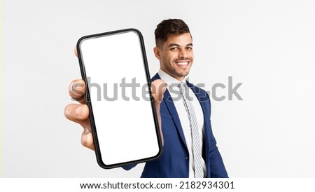 Happy Middle Eastern Businessman Showing Cell Phone With White Empty Screen And Smiling, White Studio Background. Business Mobile App Concept, Copy Space, Mockup, Collage