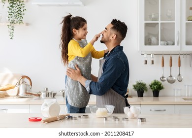 Happy Middle Eastern Dad And Little Daughter Having Fun While Baking Cookies In Kitchen Together, Cute Female Child Playfully Touching Father's Nose And Laughing, Enjoying Spending Time With Daddy - Powered by Shutterstock