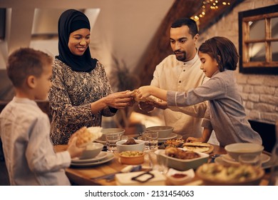 Happy Middle Eastern family sharing pita bread at dining table on Ramadan. - Shutterstock ID 2131454063