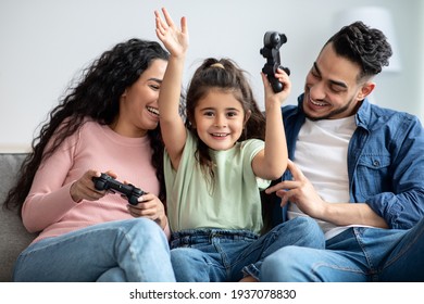 Happy Middle Eastern Family Of Three Playing Video Games Together At Home