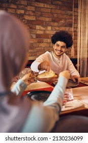 Happy Middle Eastern Man And His Wife Eating Naan Bread During Iftar Meal On Ramadan At Home.