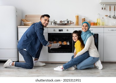 Happy Middle Eastern Parents With Little Daughter Baking Together In Kitchen, Cheerful Arab Dad Taking Tray With Freshly Baked Croissants Out Of Oven, Mother And Daughter Smiling At Camera - Powered by Shutterstock