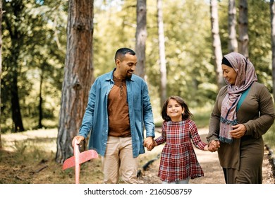 Happy Middle Eastern Parents And Their Daughter Holding Hands While Walking Through The Park.