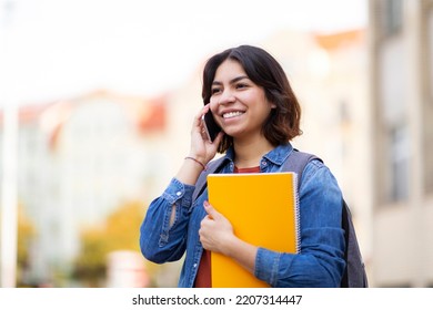 Happy Middle Eastern Student Female Talking On Cellphone While Walking Outdoors, Cheerful Young Arab Woman Holding Worbooks And Enjoying Pleasant Phone Conversation With Friend, Copy Space - Shutterstock ID 2207314447